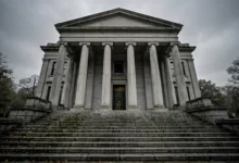 Courthouse steps with tall columns under a grey sky.