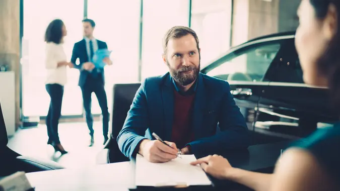 Buyer signing a $500 down no credit check car financing agreement at a dealership